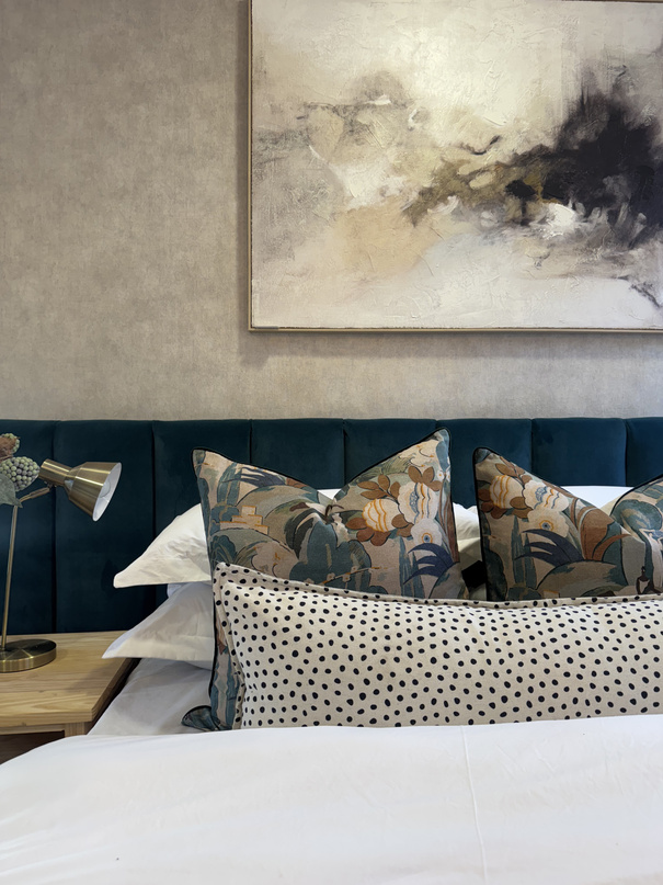 House Dart bedroom with navy headboard and layered scatter cushions
